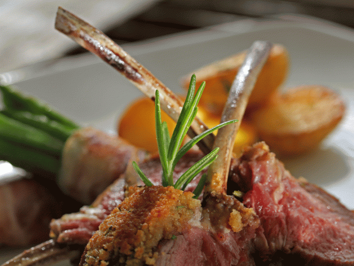 Ein gourmet angerichtetes Hauptgericht mit gebratenem rotem Fleisch, einem mit Crumble belegten Stück und Rosmarin.